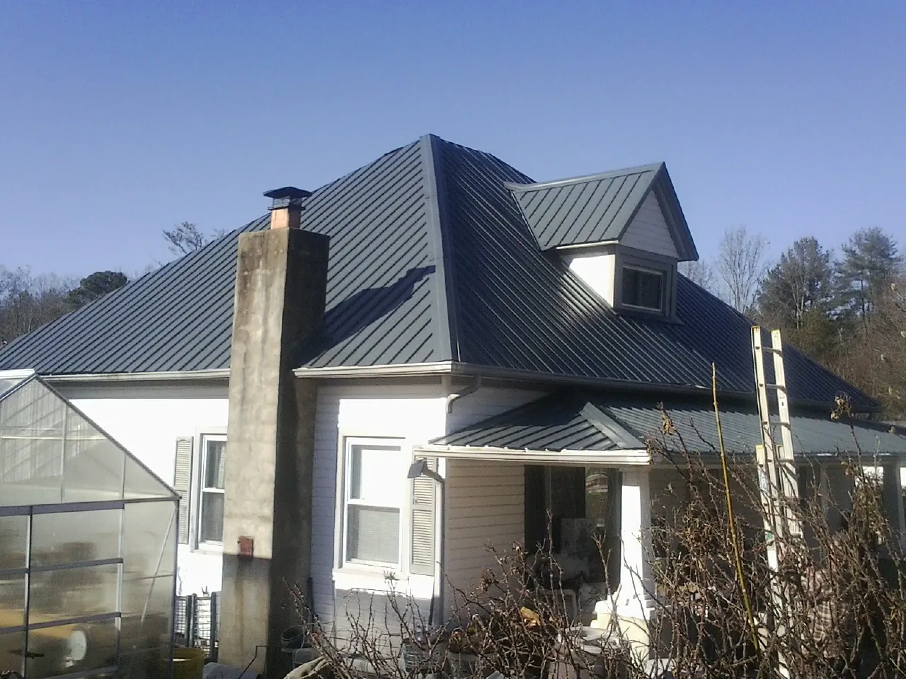 Dark blue standing seam metal roof on a white farmhouse with dormer — Slate & Tile Roof Repair by Roofing Brothers in Greenbrae