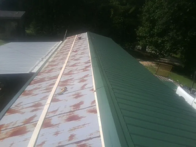 Old rusted panels beside newly installed green metal roofing — Wind Damage Roof Repair by Roofing Brothers in Greenbrae