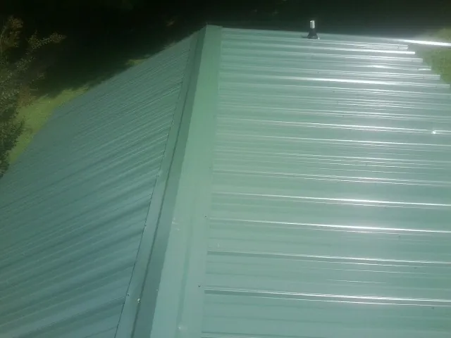 New green metal panels meeting at the ridge of a roof — Flat Roof Repair work by our crew in Greenbrae