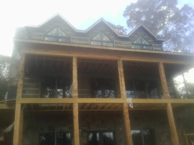 Dormers and porch framing on a large log home under construction — Roof Coating work by our crew in Greenbrae